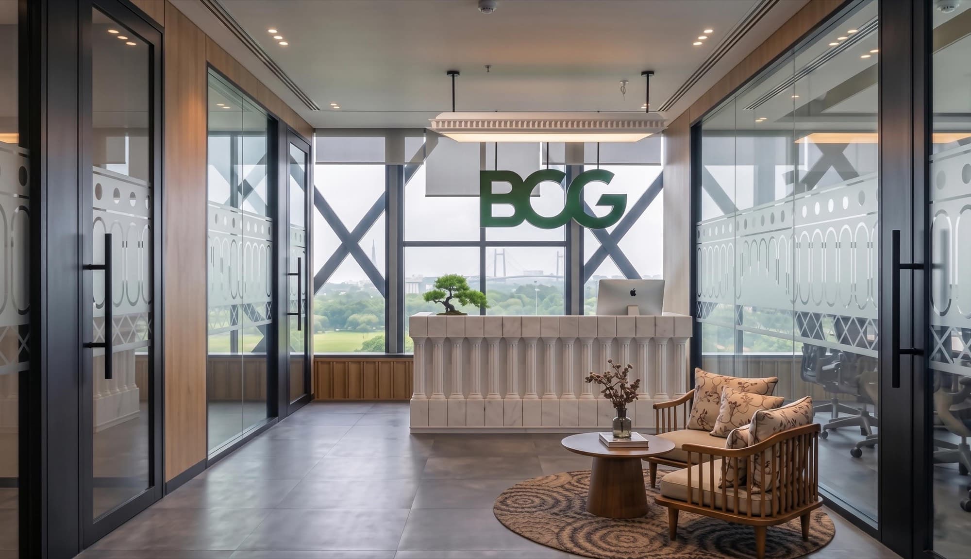 Reception with a fluted stone desk and cane lounge chairs set against a diagrid curtain wall